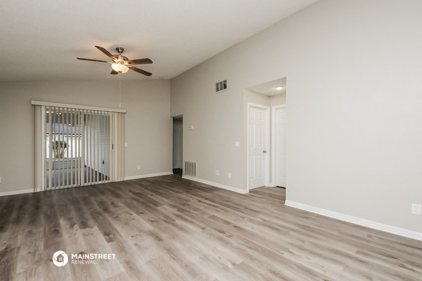 the living room of an empty house with a ceiling fan