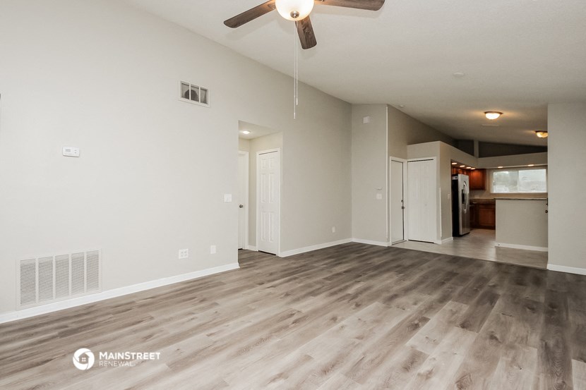 an empty living room with a ceiling fan