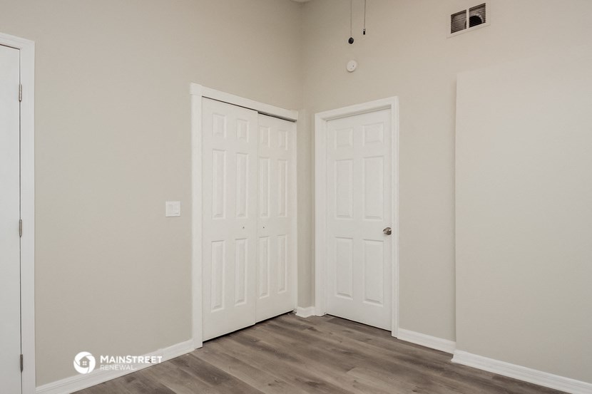 a bedroom with two doors and a door to a closet