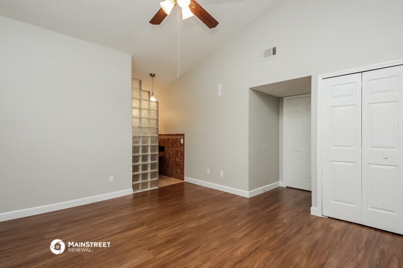 an empty living room with wood flooring and a ceiling fan