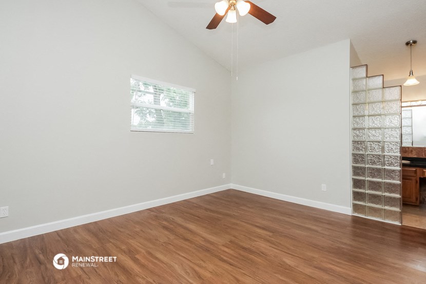 an empty living room with a wood floor and a ceiling fan