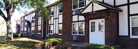 A white door is on the right side of a brick building.