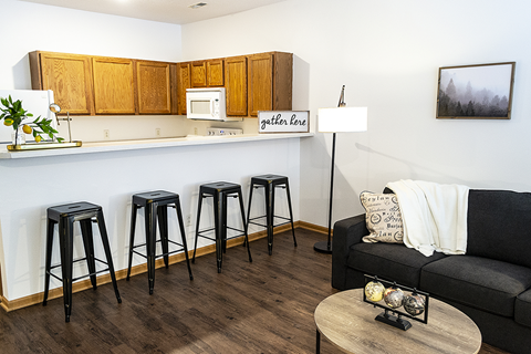 a living room with a bar and a kitchen with stools