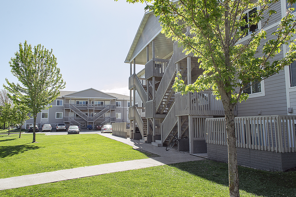 a view of the exterior of a building with stairs and a green lawn