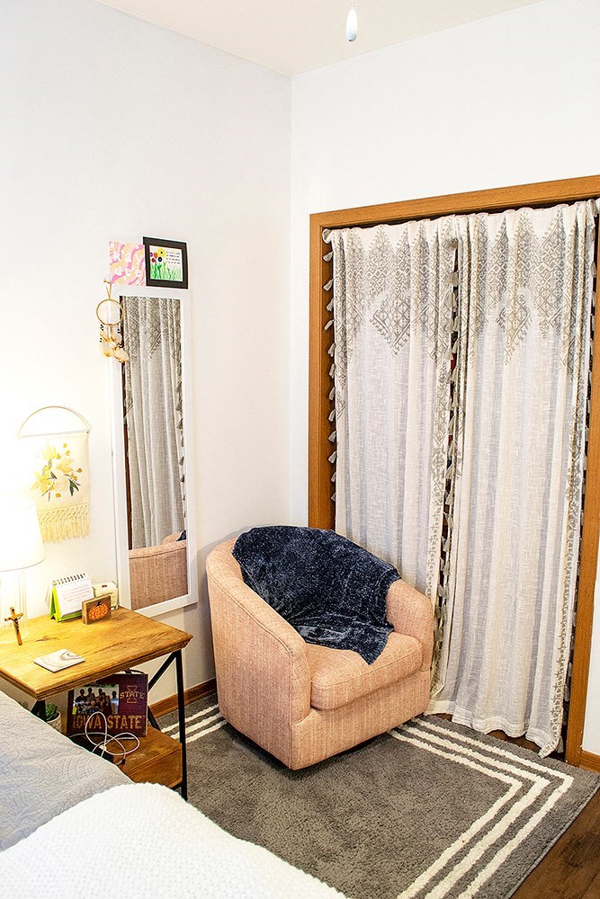 a room with a chair and a curtain and a bed