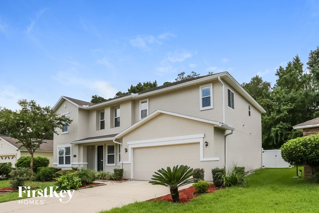 a beige house with a driveway and a lawn