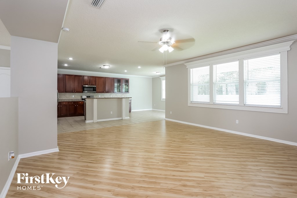 the living room and kitchen with wood flooring and a ceiling fan