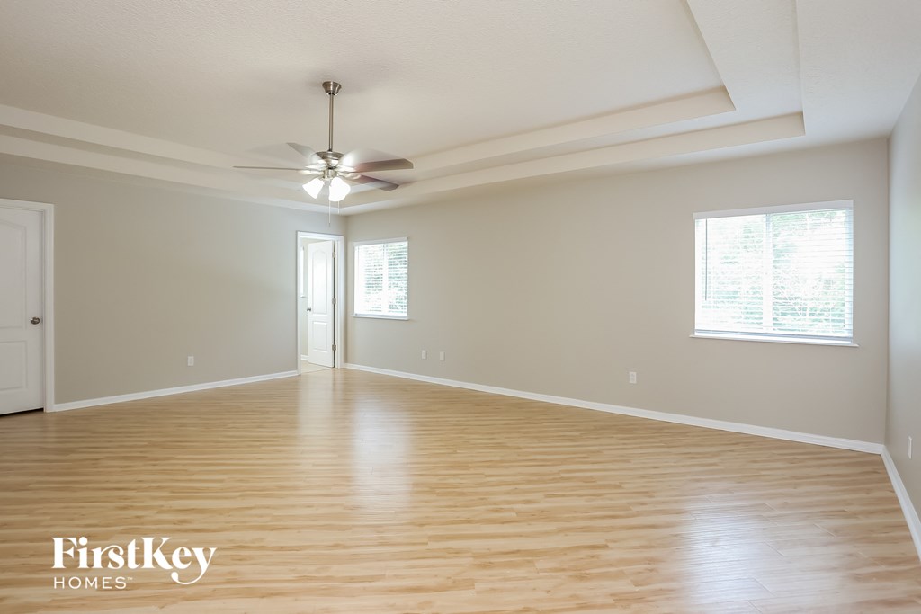 an empty living room with wood floors and a ceiling fan