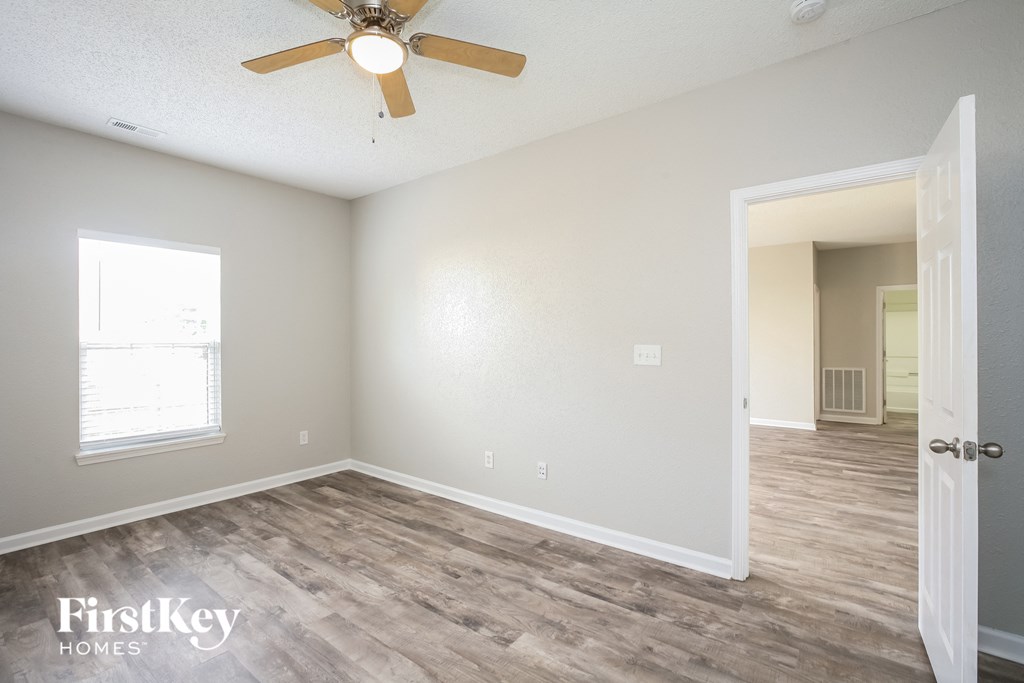 the spacious living room with hardwood flooring and a ceiling fan