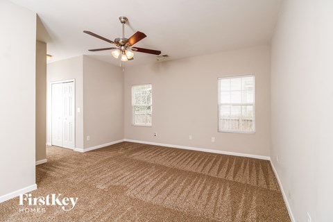 a living room with carpet and a ceiling fan