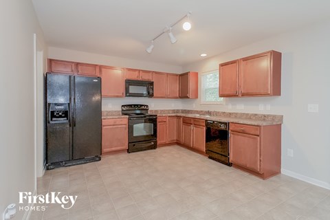 A kitchen with a black fridge and microwave, and a stove with an oven.