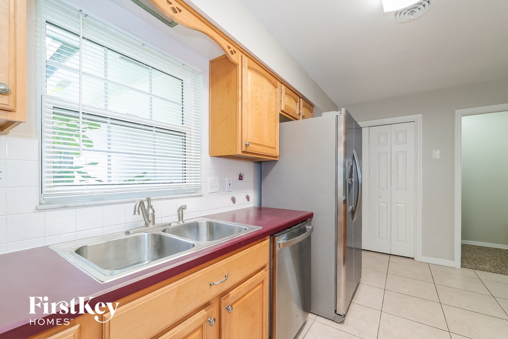 A kitchen with wooden cabinets and a stainless steel refrigerator.