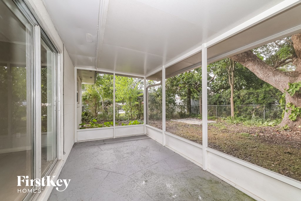 A sunny day in a room with a view of trees through the windows.