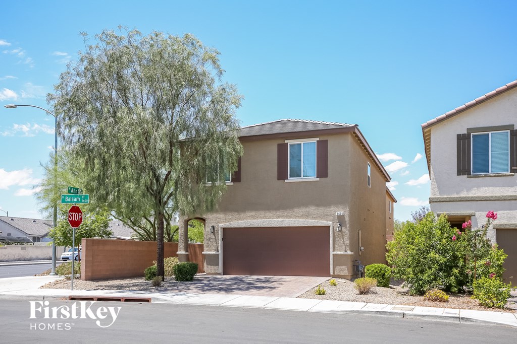 a house with a garage door and a tree in front of it