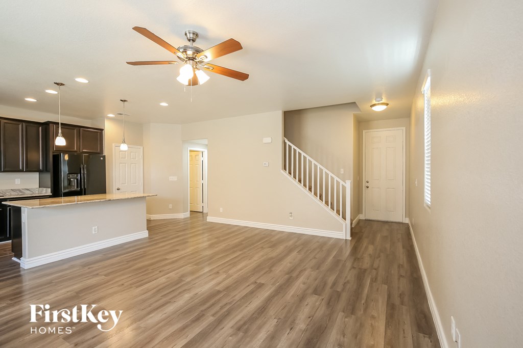 an open living room and kitchen with wood flooring and a ceiling fan