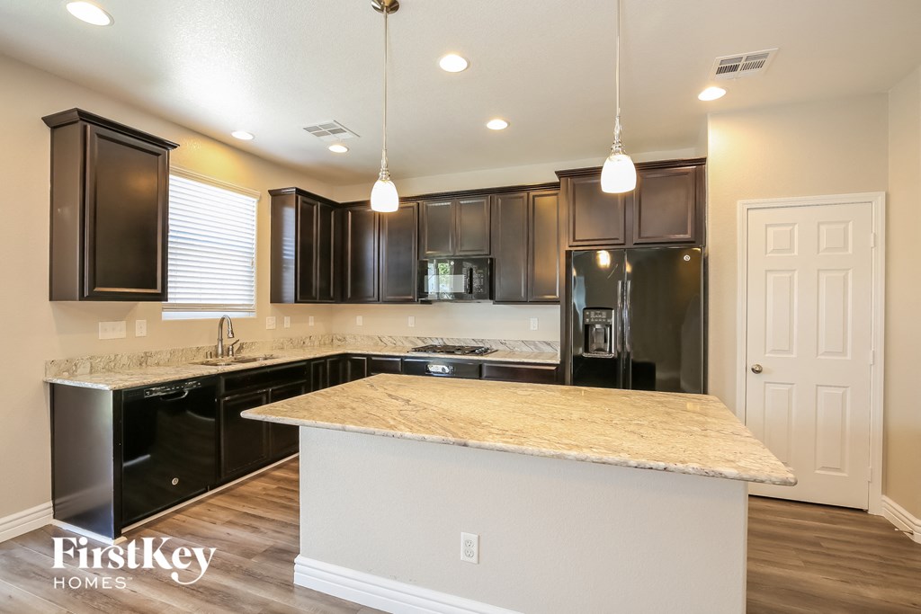 a kitchen with black appliances and a marble counter top
