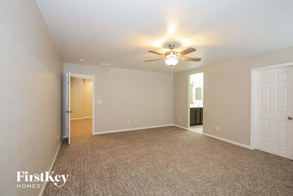 a spacious living room with carpet and a ceiling fan