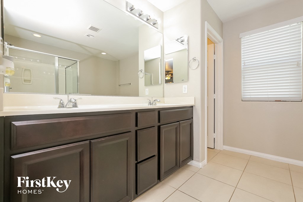the master bathroom has a large vanity with two sinks and a large mirror