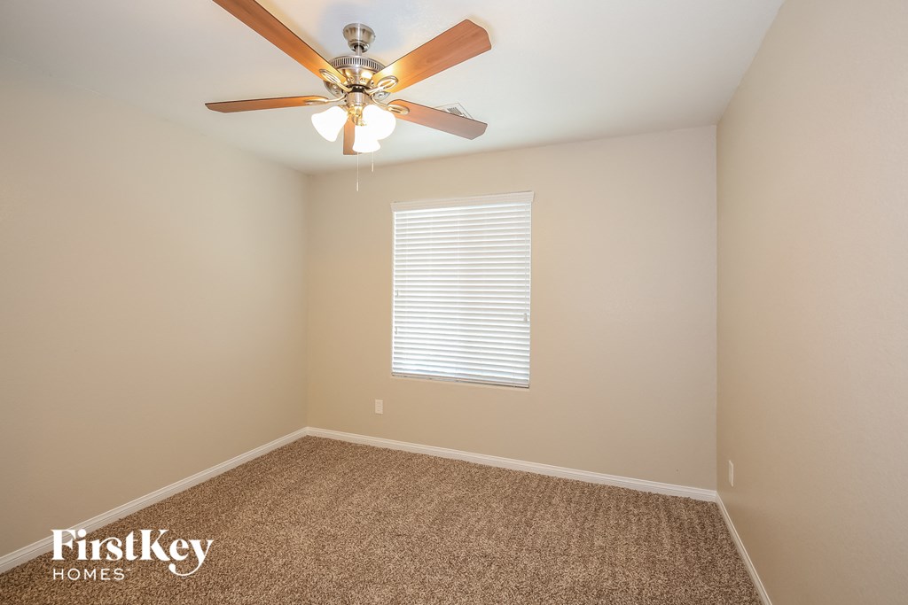 the upstairs bedroom has a ceiling fan and a carpet