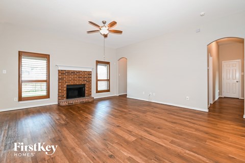 A spacious room with a fireplace and wood flooring.