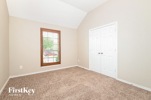 A room with a white door and a window with a view of trees.