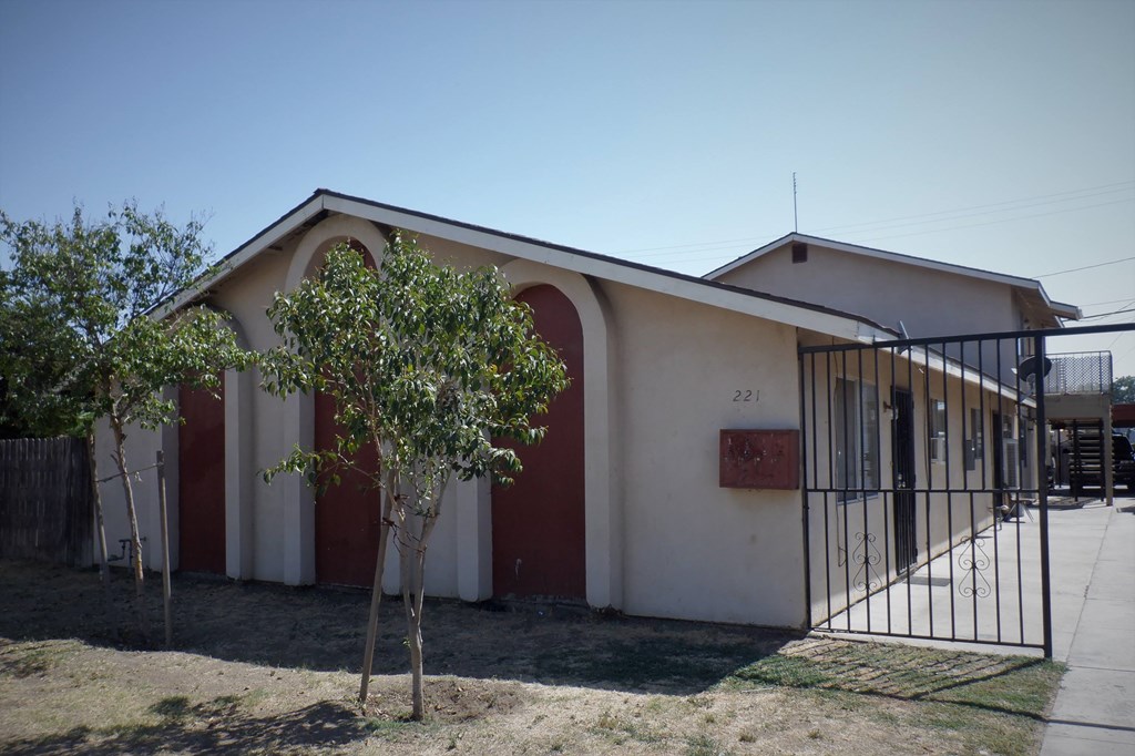 the front of a church with two trees and a metal gate