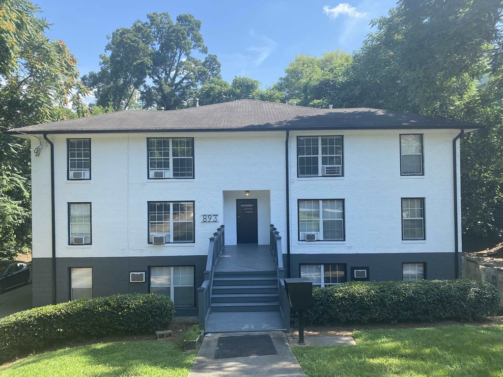 the front of a white house with black stairs