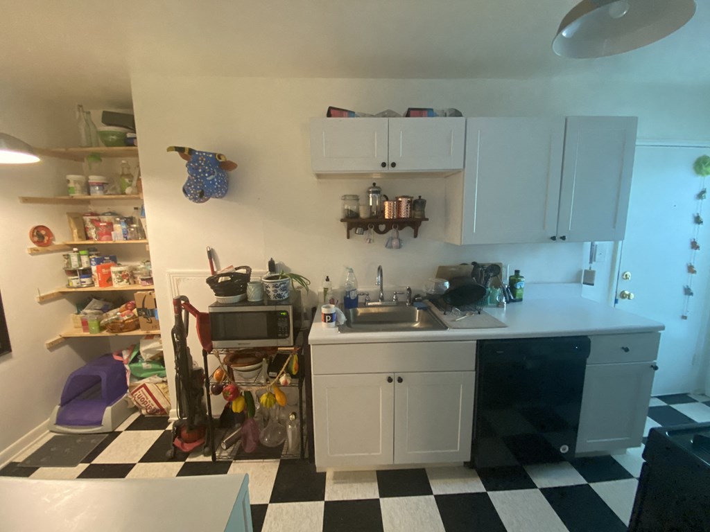 a kitchen with a black and white checkered floor and white cabinets