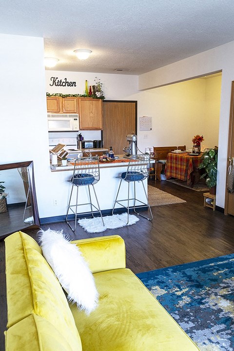 a living room with a kitchen and a yellow couch