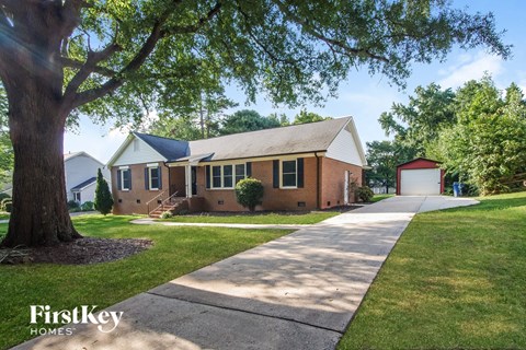 a small brick house with a sidewalk and a tree