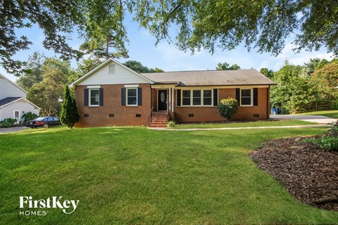 front view of a brick house with green grass and trees