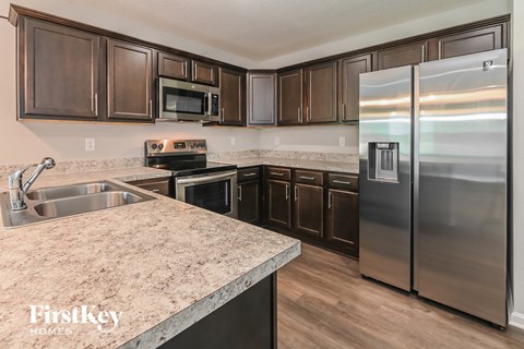 A kitchen with a stainless steel refrigerator and wooden cabinets.