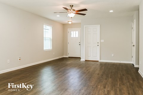 A spacious room with wooden floors and a ceiling fan.