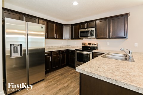 A kitchen with a stainless steel refrigerator and wooden cabinets.