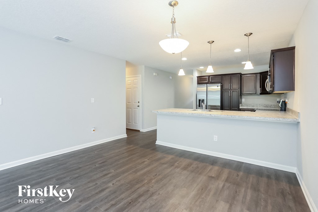 the living room and kitchen of an apartment with wood flooring