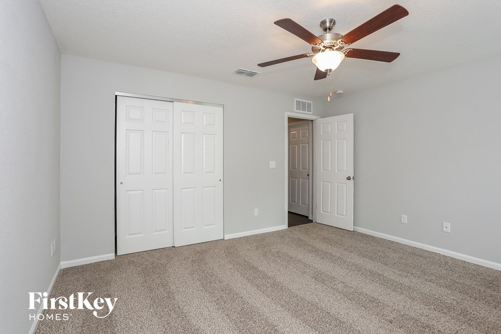the living room is spacious and has a ceiling fan