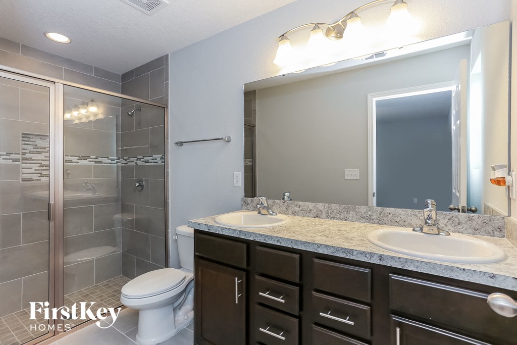a bathroom with a toilet sink and mirror and a shower