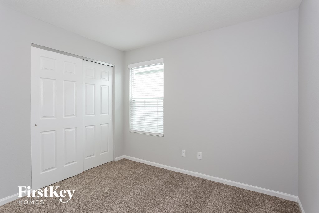 a bedroom with white walls and a white door and a window