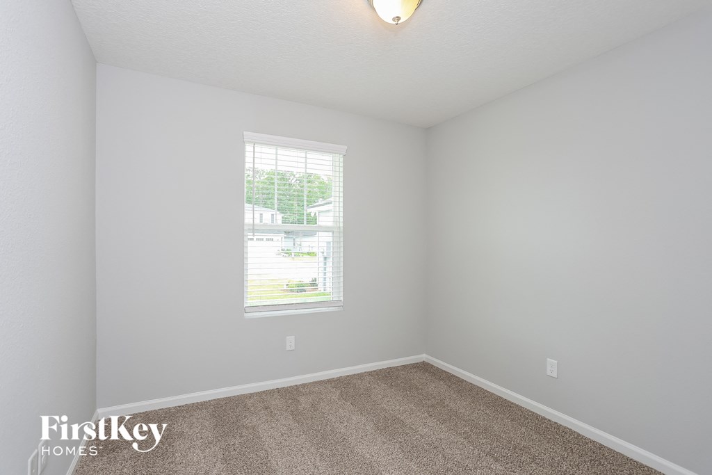 a bedroom with white walls and a window