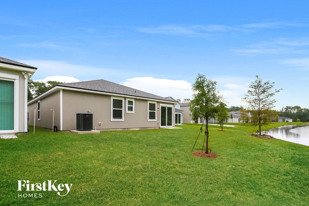 a home with a lake in the background and a grassy yard