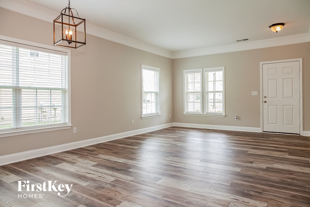 the living room of an empty house with a white door and windows