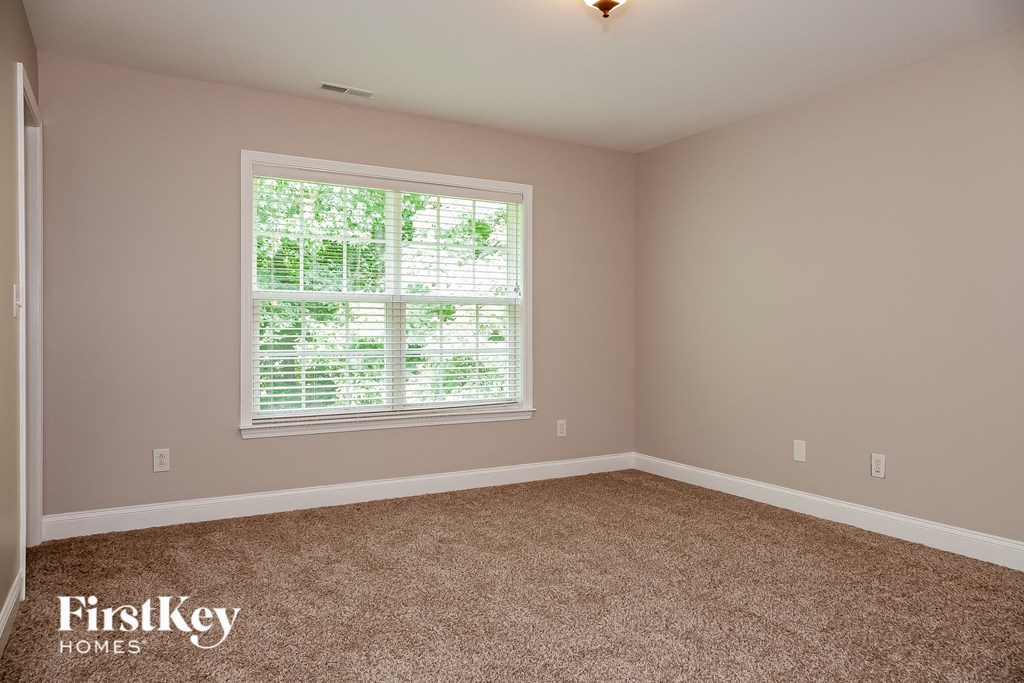 a bedroom with a large window and a carpeted floor