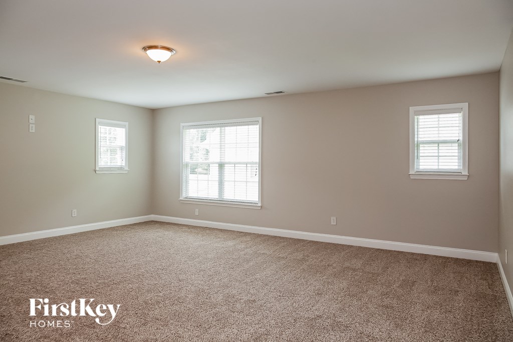 a large empty room with carpet and two windows