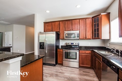 A kitchen with wooden cabinets and a black counter top.