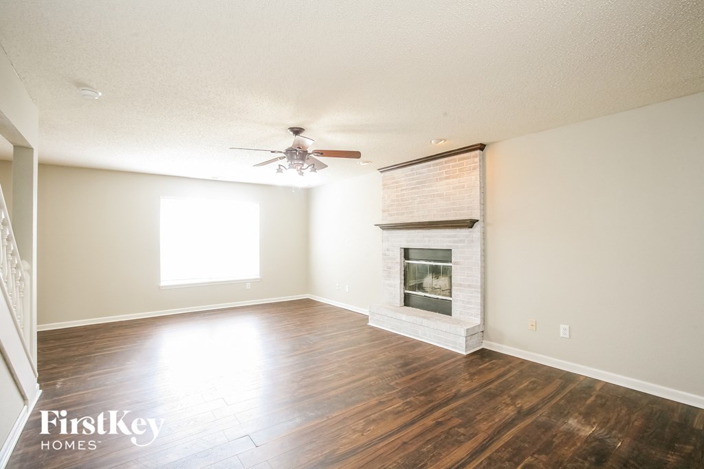an empty living room with a fireplace and a ceiling fan