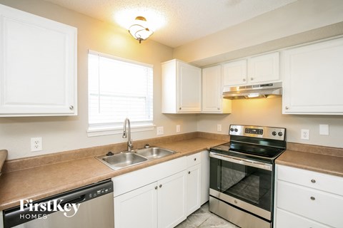 a kitchen with white cabinets and a sink and a stove