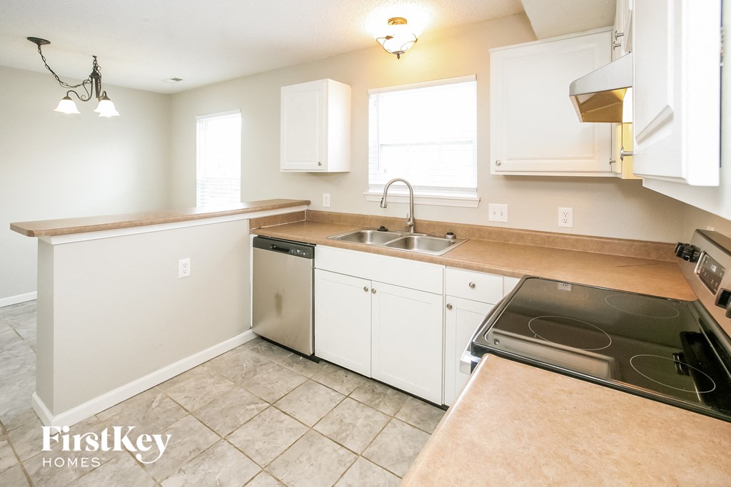 a kitchen with white cabinets and a stove and a sink