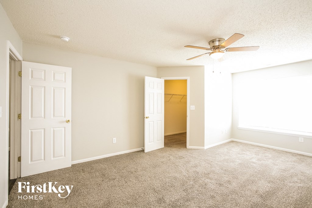 a bedroom with a ceiling fan and a door to a closet