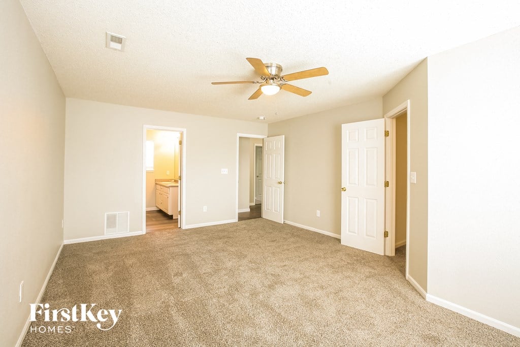 a spacious living room with carpet and a ceiling fan