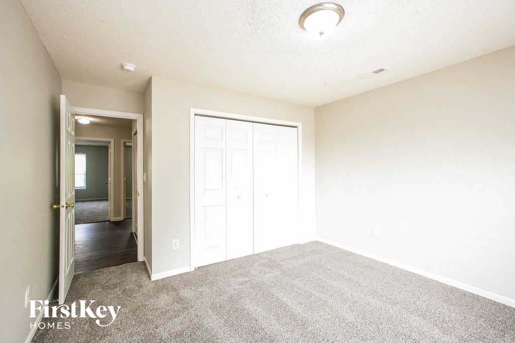an empty living room with carpet and a door to a hallway
